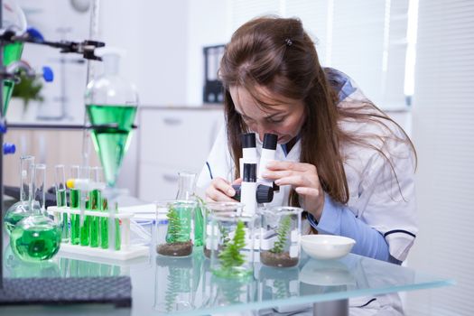 Female scientist adjusting her microscope in a biotechnology lab. Research lab. Academic scientist.