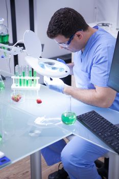 Young man in a research lab doing test on a strawberry in a agriculture research lab. test tubes.