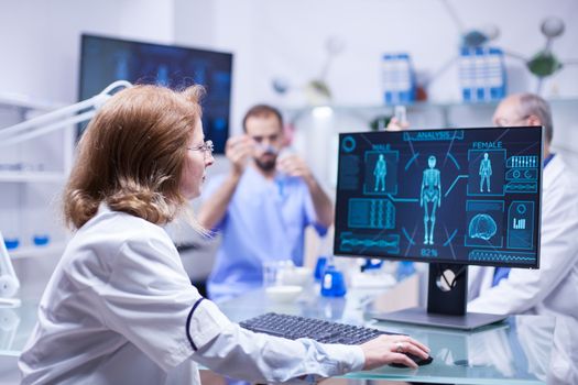 Middle age female scientist working a in laboratory typing a report on computer. Computer operator.