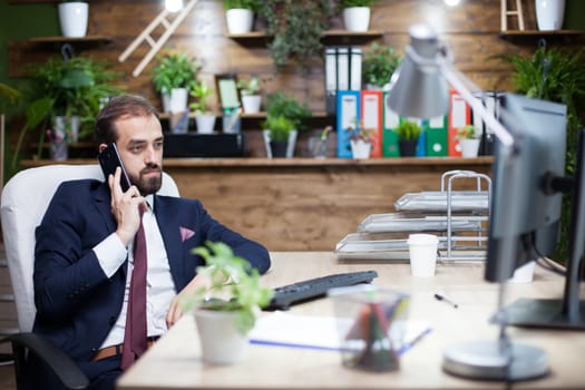 Heandsome bearded businessman in suit havine conversation on his mobile phone. Elegant businessman in his office.
