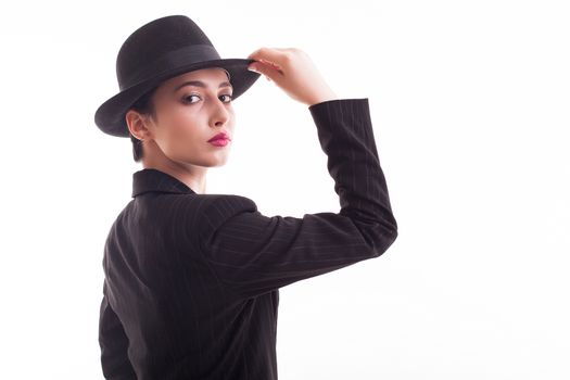 Beautiful young model with a stylish black hat over white background in studio. Retro fashion style.