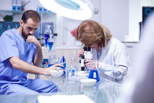 Female scientist looking through a microscope in laboratory. Young engineer holding a biological sample.