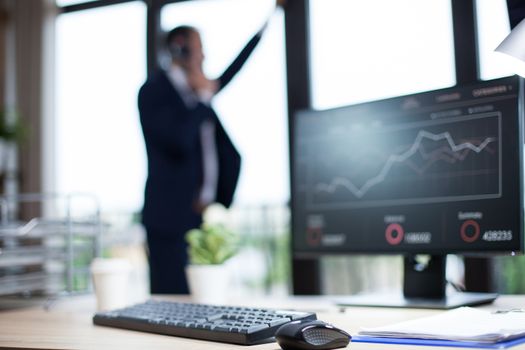 Computer monitor with graphics in a business office. Entrepreneur in the background.