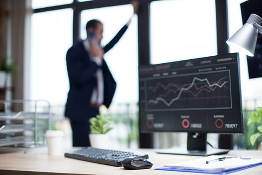 Marketing data displayed on computer monitor in a business person office. Young businessman in the background.