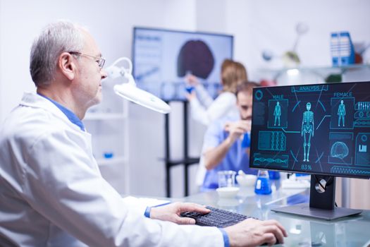 Experienced senior technician working on computer in a laboratory science. Senior engineer typing.