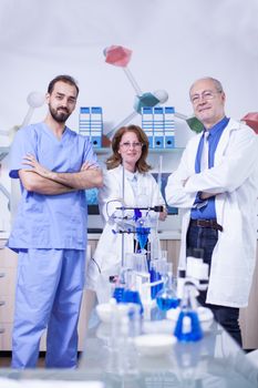 Female scientist smiling to the camera with her colleagues by her side in laboratory. Laboratory equipment.