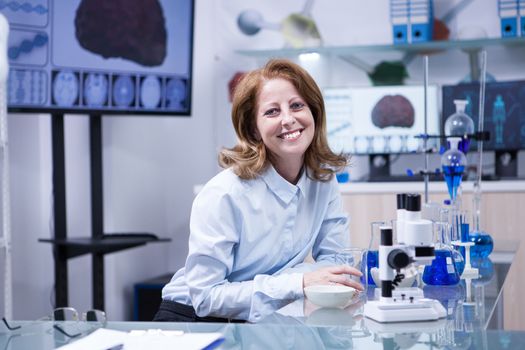 Smiling senior doctor woman working with microscope at laborator. Modern scientist.