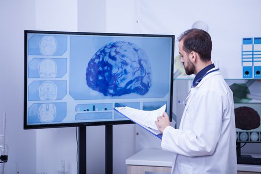 Doctor checking the brain analyzes of a patient on his clipboard. Specialist doctor in brain healthcare.