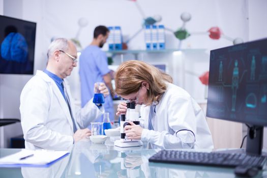 Female and senior scientist working together in a research laboratory. Scientist working on microscope.