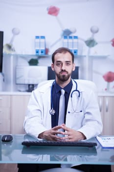 Young and inteligent doctor in his cabinet wearing a white coat and his stethoscope. Confident young doctor. Cheerful doctor.