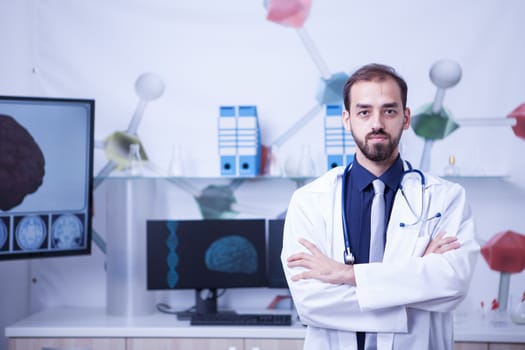 Handsome young doctor with arms crossedin his cabinet at the hospital. Young and motivated doctor.