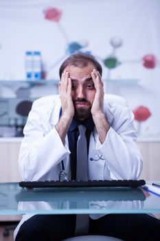 Portrait of young burnout doctor in his hospital cabinet. Young doctor overload of work at the hospital cabinet.