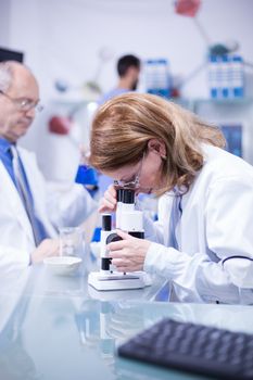 Female engineer with a white coat working under a microscope in a laboratory. Moder laboratory.