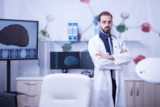 Full lenght portrait of young doctor with arms crossed looking at the camera. Young cardiologist.