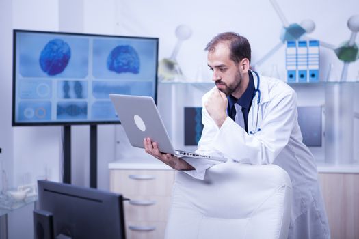 Handsome young doctor having a video call with another doctor in his cabinet. Doctor in a hospital cabinet.