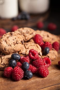 Close up photo of tasty blueberries with delicious chocolate chips. Chocolate cookies with milk.