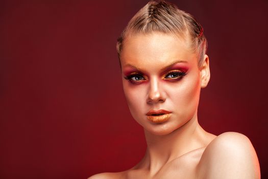 High Fashion model woman with stylish makeup on red background. Makeup trends. Golden eyebrows. Pink makeup. Beauty makeup. Beautiful woman.