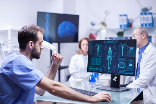 Portrait of young scientist looking at monitor computer checking male body. Team of engineers working in science laboratory.