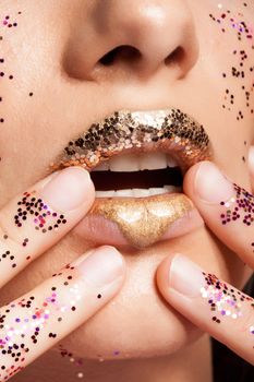 Woman with golden lips and glitter on her hands in studio. Beauty shot. Fashion shot. Beauty makeup.