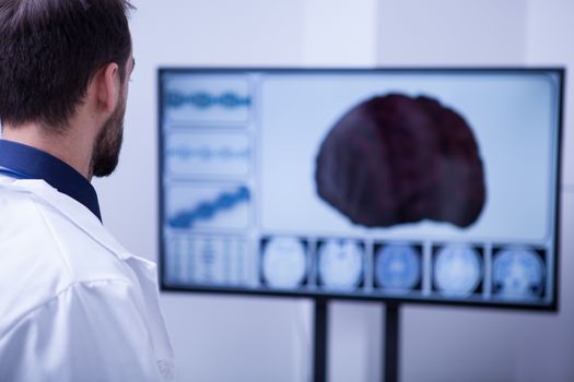 Young male surgeon using technology to check out a patient brain. Brain on the screen.