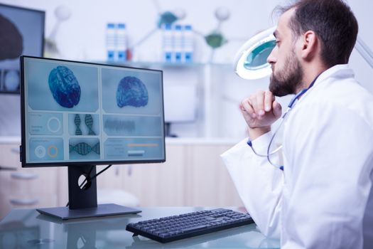 Young male doctor specialised in brain tumor checking a bran in hospital laboratory. Brain examination.