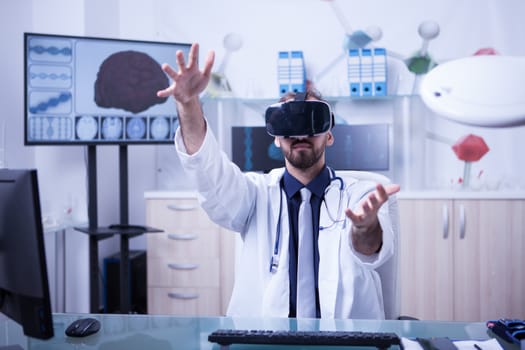 View of a male doctor holding a 3d rendering using virtual reality headset. Doctor in his office working.