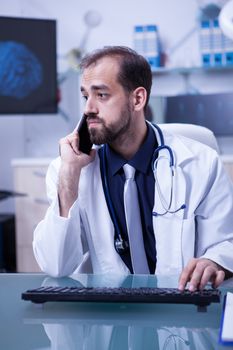 Young doctor consulting with a colleague over phone call regarding a brain injury. Doctor using smartphone.