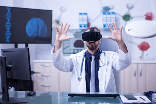 Caucasian male doctor wearing virtual reality glasses testing patient results. Inovative technology for doctors.