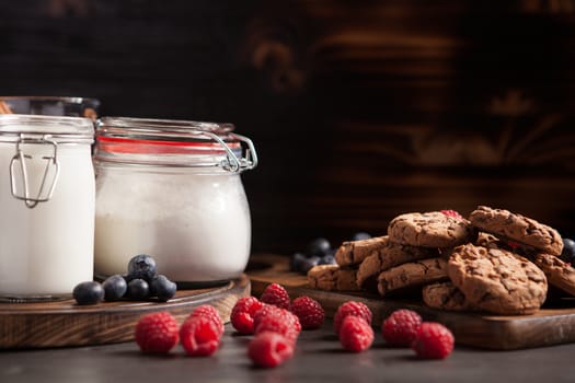 Delicious and freshly baked cookies stacked on wooden table. Tasty milk.