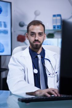 Portrait of attractive caucasian doctor looking into the camera sitting at his office. Handsome doctor.