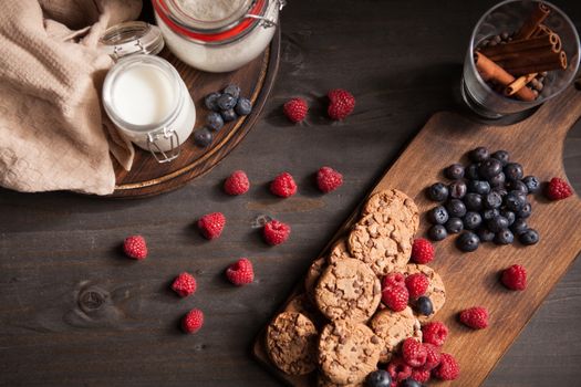 Tasty and delicious chocolate chips out of the oven on a wooden plate. Blueberries and rasppberries.