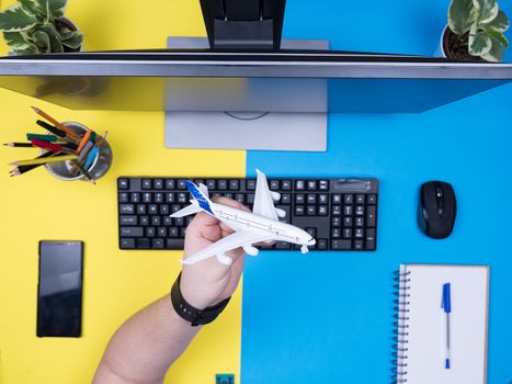 Flat lay top view of business man hands holding a toy plane. Traveler entrepeneur.
