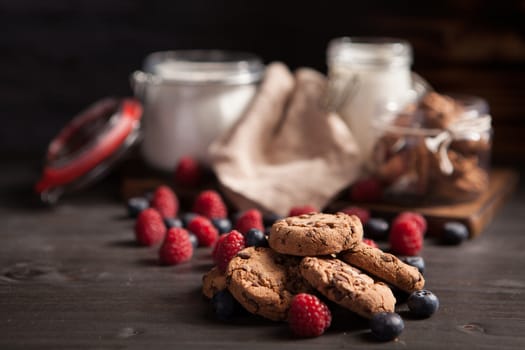 Homemade tasty and delicious chocolate chips on rustic wooden table. Fresh bluebarries and raspberries.