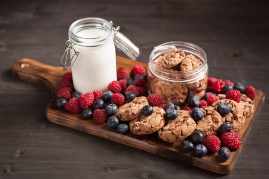 Fresh milk next to delicious chocolate chips with dark chocolate. Tasty biscuits.