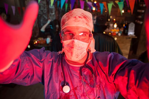 Attractive young man dressed up like a scary doctor celebrating halloween with his monster friends. Halloween tradition.