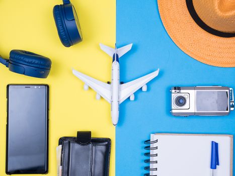 Flat lay top view blue background with a variety of accesorries for travelers. Orange hat. Modern and small camera.