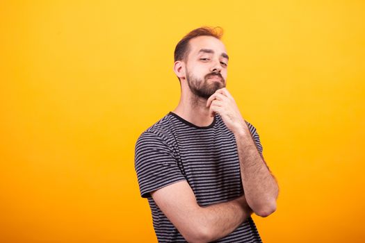 Portrait of thoughtful young man looking into the camera looking at the camera over yellow background.