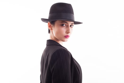 Attractive young female wearing a retro black hat in studio over white background. Stylish young model.