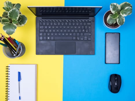 Flat lay top view of modern notebook with black phone next to.