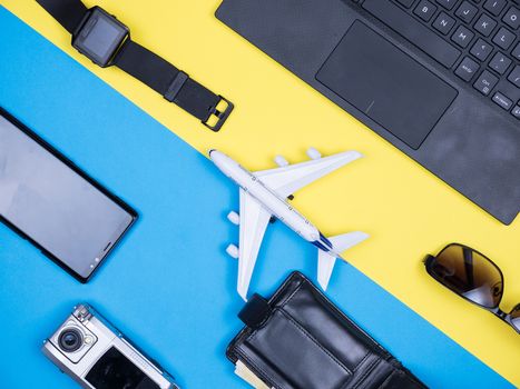 Flat lay top view of modern toy plane over blue background. Modern phone. Stylish sunglasse. Traveler hand watch.