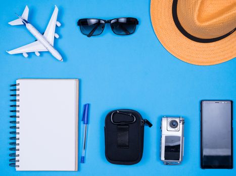 Flat lay top view accessories of traveler journalist over blue background. Stylish hat. Modern camera.