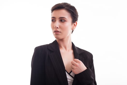 Attractive young woman wearing a black jacket looking on her right over a white background. Costume jacket.