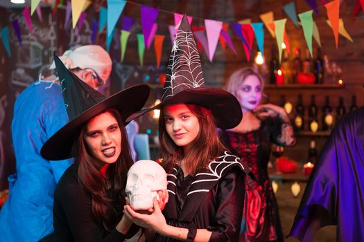 Big sister and her little sister dressed up like witches at halloween celebration. Halloween costumes.