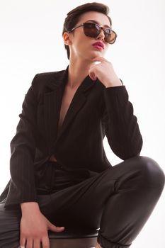 Beautiful young fashion model with sunglasses posing in studio over white background. Full body portrait. Posing with hands.
