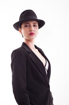 Portrait of beautiful young woman with short hair wearing a stylish black hat over white background in studio. Retro hat.