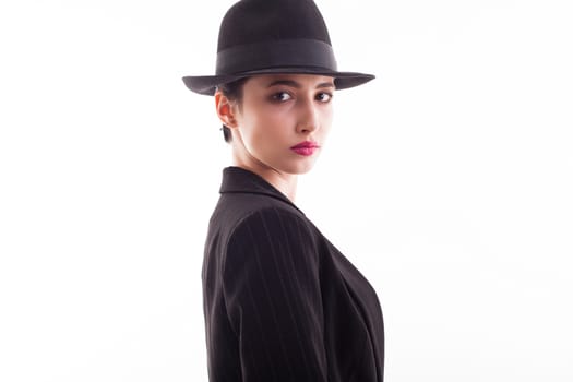 Side view portrait of gorgeous young female wearing a retro black hat in studio over white background. Fashion studio.