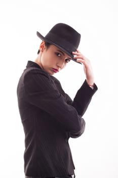 Glamorous female posing in studio wearing a black jacket with a stylish hat. Caucasian beauty.