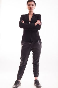 Full body portrait of beautiful young woman posing with arms crossed in leather pants over white background. Fashion model.