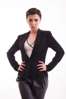 Beautiful young woman in black jacket keeping hands on her waist. Girl posing over white background.