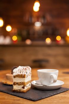 Delicious chocholate cake with white cream and cinnamon on top. Cup of delicious coffee. Delicious dessert. Traditional dessert with fresh ingredients.